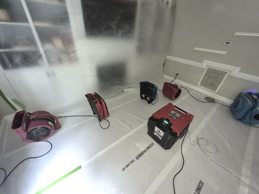 Professional drying chamber with dehumidifiers, air movers, floor protection, and containment following a toilet overflow water damage loss in Fuquay Varina NC