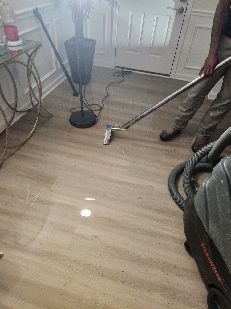 EMERG+NC technician extracting standing water from luxury vinyl plank flooring after an upstairs bathroom water supply line leak in Clayton, NC.