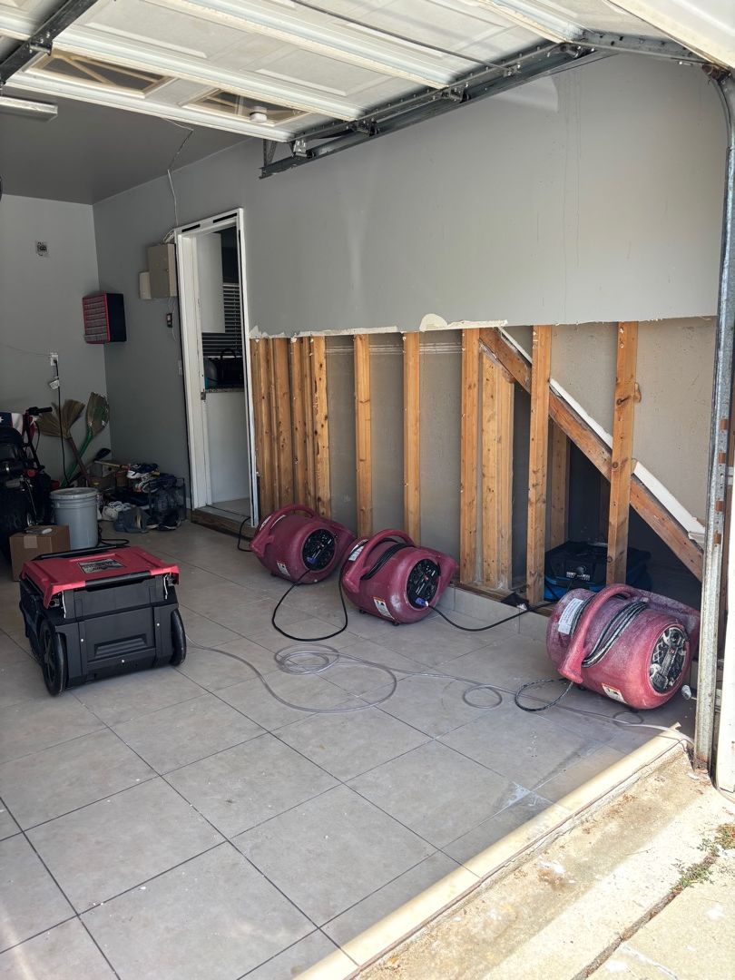 Air movers drying wall cavities after flood cuts in Raleigh NC garage water damage restoration project