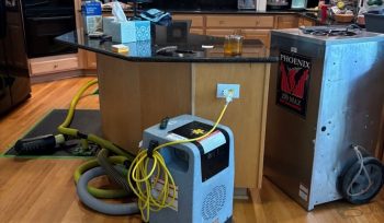 Specialty hardwood floor drying mats installed on water-damaged hardwood flooring in a Fuquay-Varina, NC kitchen.
