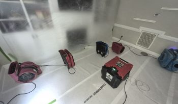Professional drying chamber with dehumidifiers, air movers, floor protection, and containment following a toilet overflow water damage loss in Fuquay Varina NC