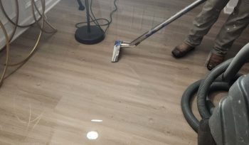 EMERG+NC technician extracting standing water from luxury vinyl plank flooring after an upstairs bathroom water supply line leak in Clayton, NC.